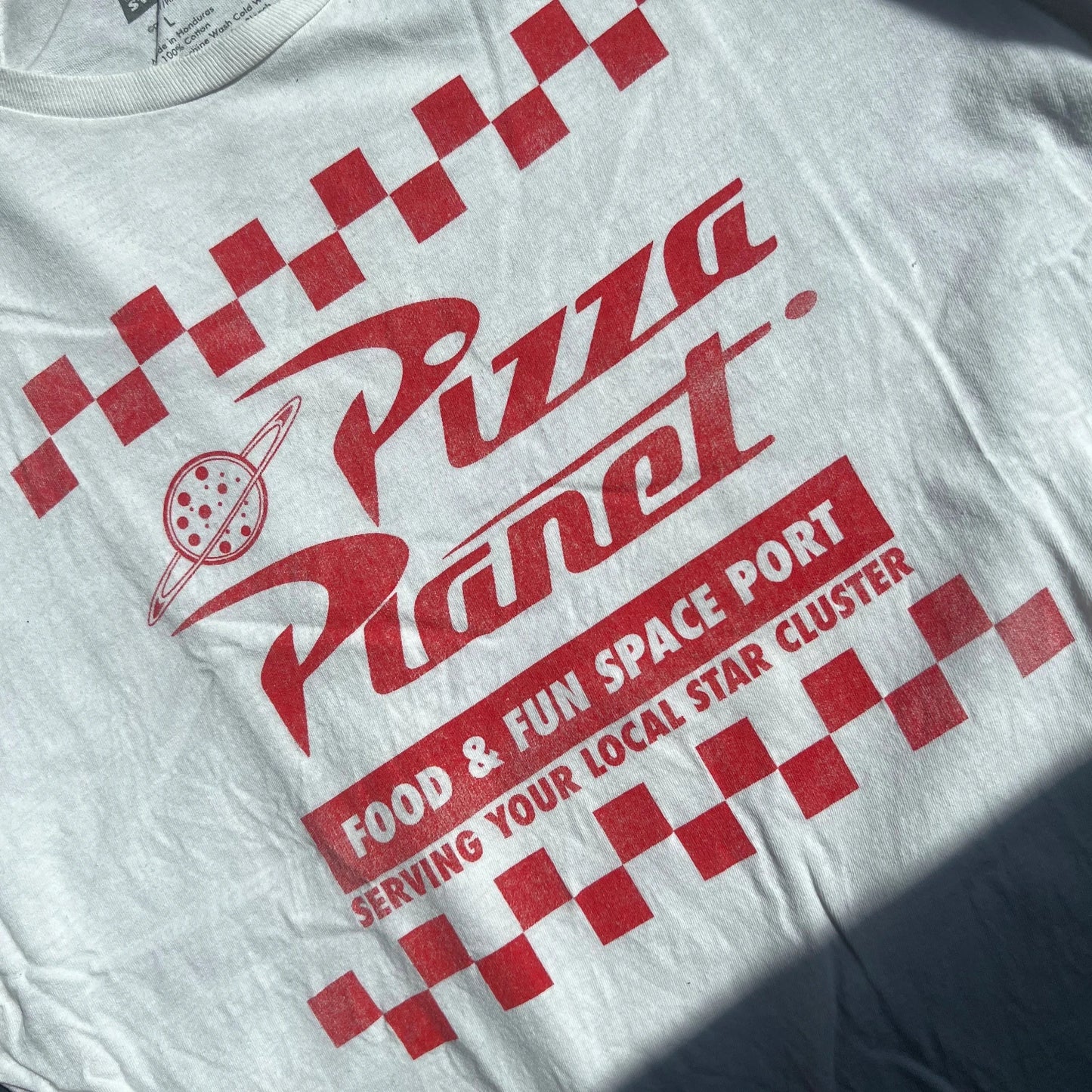 White t-shirt with red 'Pizza Planet' graphic and text. Fun & Fun Space Port