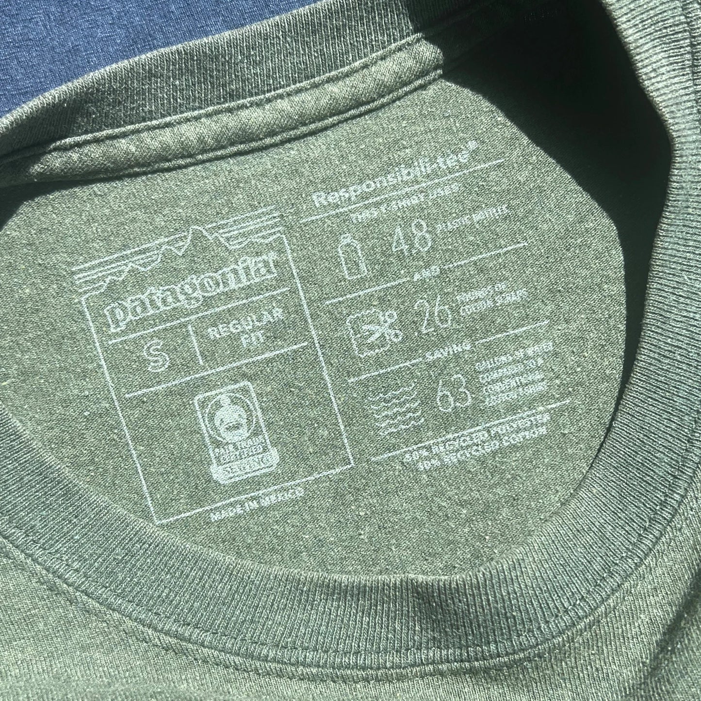 Close-up of army green long sleeve carelabel included garment information
