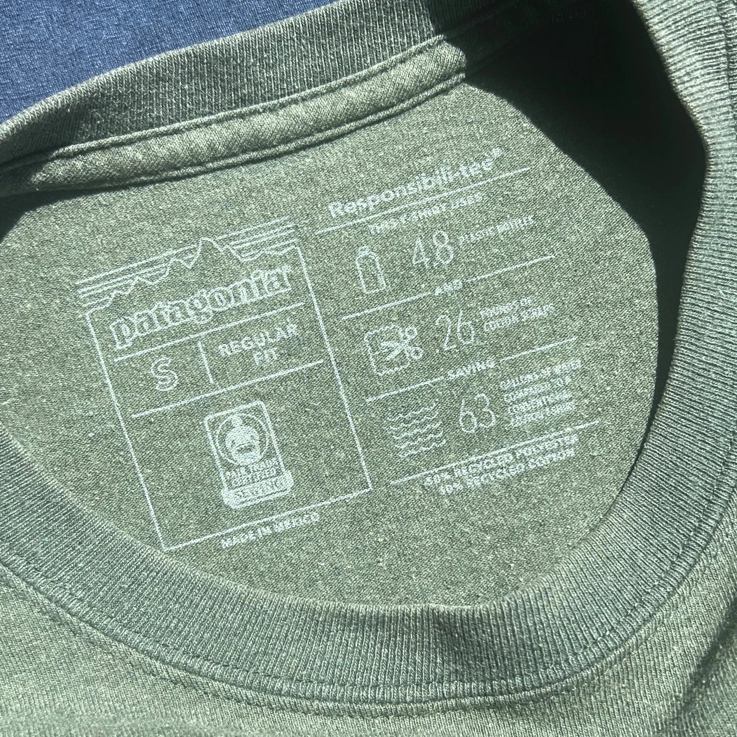 Close-up of army green long sleeve carelabel included garment information