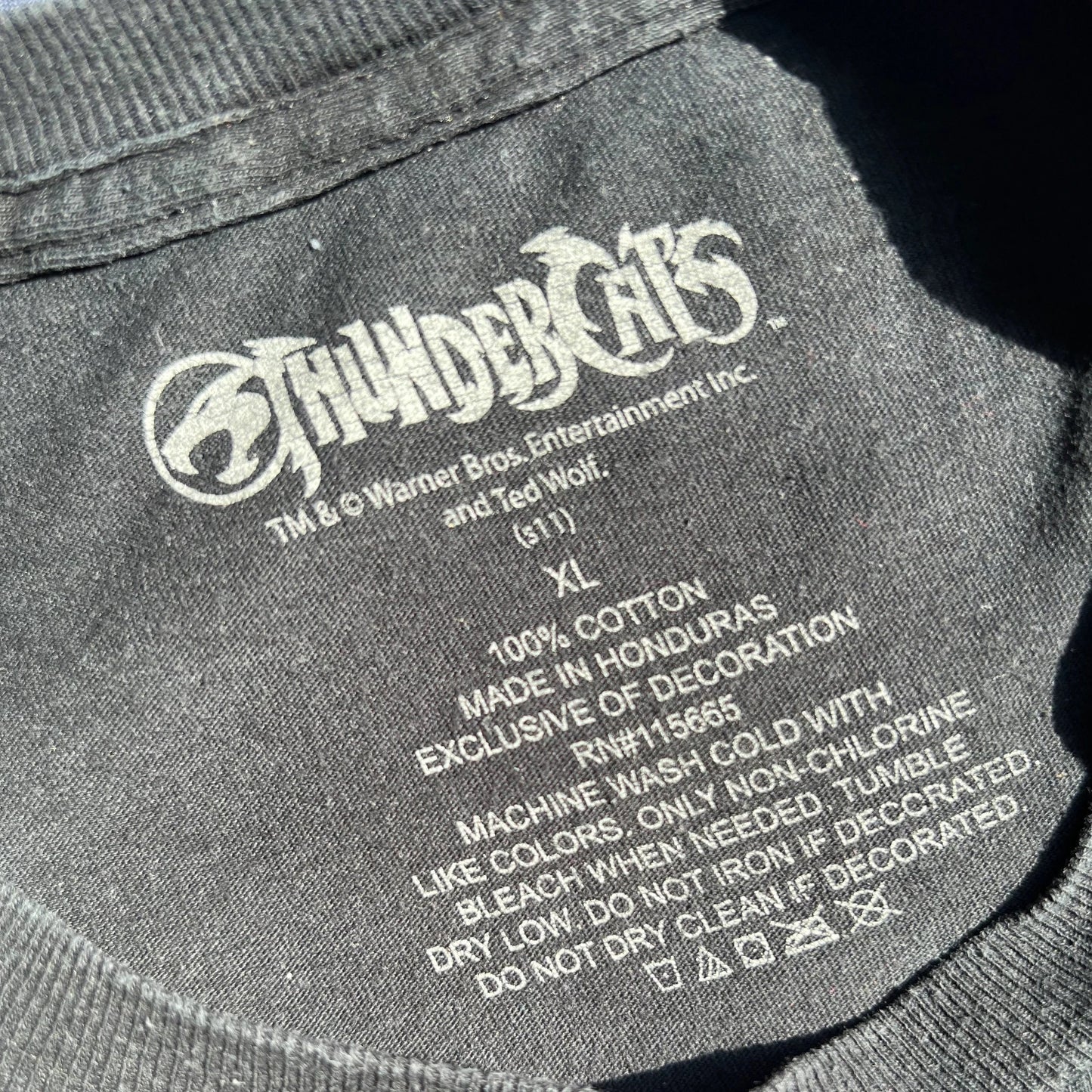 'ThunderCats' logo and garment information on a black t-shirt